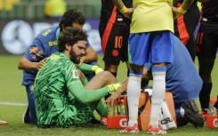 Alisson Becker receives treatment on the pitch after his collision with Colombia defender Davinson Sanchez