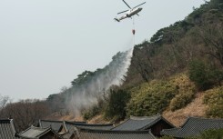 A helicopter drops water as a wildfire advances towards Gounsa Temple in Uiseong