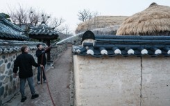 Firefighters are spraying water on thatched roofs in Hahoe Folk Village, which is UNESCO listed