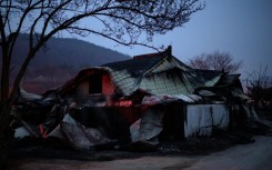 A house glows after being torched by a wildfire in Cheongsong