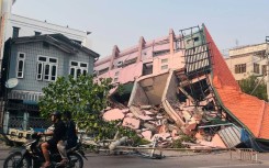 A motorbike drives past a collapsed building in Mandalay, which was badly hit by the magnitude 7.7 quake