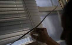 Rosario peers through her window blinds for any lurking US ICE agents outside her building