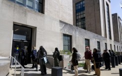 Federal workers wait in line to access to the Mary E. Switzer Memorial Building that houses the US Department of Health and Human Services in Washington, DC