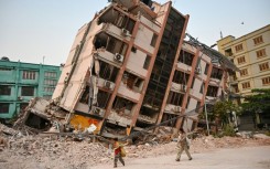 Children walk past a toppled building in Mandalay, five days after the deadly quake