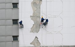Workers repair damage on the exterior of a high-rise building in Bangkok following the March 28 earthquake
