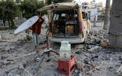 A man carries a satellite dish near a damaged media van after the strike which Israel's military said targeted Hamas militants who used the hospital facility