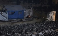 A displaced Palestinian woman cooks a meal on the stage of the auditorium in the heavily damaged Islamic University campus in Gaza City, where Palestinian families have taken refuge