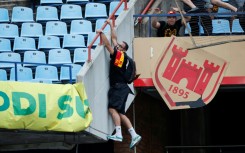 An Esperance supporter clings to a railing at a Pretoria stadium during crowd violence after a CAF Champions League match against Mamelodi Sundowns on April 1.