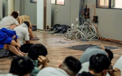 Alleged scam centre workers beside dismantled electronic appliances during a crackdown operation in Myanmar