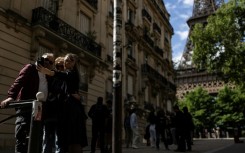 Three pedestrians take a selfie on the picturesque alleyway at the end of Rue de l'Universite, Paris