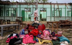 Over a dozen abandoned book bags were piled before a pole flying the Myanmar flag outside the school building