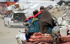 A Palestinian woman sits atop her family belongings as people flee Gaza City
