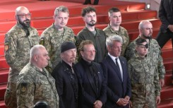 Bono, The Edge and US actor Sean Penn pose with Ukrainian soldiers on the Cannes red carpet