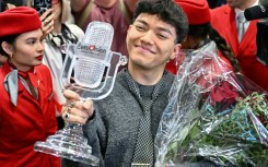 The smiling winner stepped off the plane clutching a bouquet of red roses and his trophy