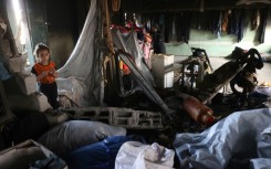 Palestinians look through the debris in a classroom after a strike hit a school serving as a shelter for displaced people