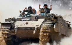 Israeli soldiers gesture atop a military vehicle at Israel's southern border with the Gaza Strip