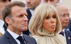 Grim day: France's President Emmanuel Macron and his wife Brigitte Macron at a wreath-laying ceremony in Hanoi Monday