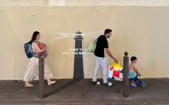 Pedestrians walk past a newly released artwork by street artist Banksy on the facade of a building in Marseille in southern France