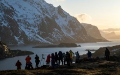 Tourists photograph a fjord in Norway's Lofoten Islands