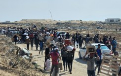 Displaced Palestinians walk along a road to receive humanitarian aid packages from a US-backed foundation in Rafah