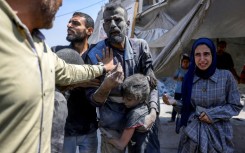 An injured Palestinian child embraces a relative that was pulled from the rubble in the northern Gaza Strip