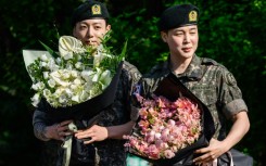 (L-R) Jungkook and Jimin of K-pop supergroup BTS hold bouquets of flowers shortly after their release from 18 months of South Korean military service