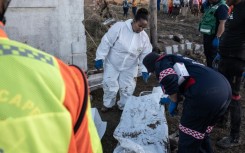 Forensics personnel write on a body bag after finding victims of the flooding near Mthatha as the death toll hit at least 78