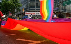 Participants in South Korea's annual Pride parade in Seoul carry a huge flag in support of LGBTQ rights past opponents holding a banner that reads "Homosexuality is sin!"
