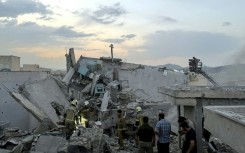 First responders clamber over the rubble of a Tehran building hit by an Israeli strike.