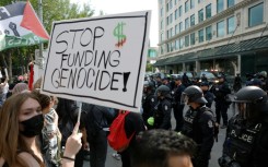 A protester holds a sign during a demonstration in front of Calgary City Hall on June 15, 2025, as world leaders converge in Canada for the G7 Summit