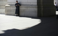 A chef takes a break to check his phone in a sliver of shade outside Union Station on August 12, 2016 in Washington,DC