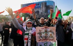 Iranians wave flags and placards during a rally protesting the US attack on Iran in Enghelab Square in Tehran