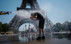 A municipal employee sprays water to cool off tourists in front of the Eiffel Tower in Paris, on July 2, 2025, as a heatwave hits France