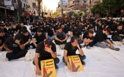 Hezbollah supporters hold a sign that reads: "We will not relinquish arms"