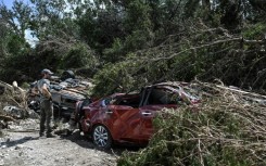 A man searches for missing people by a crushed car near the Guadalupe River in Hunt, Texas
