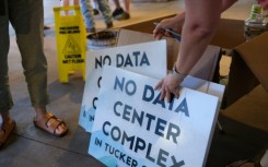 Volunteers hand out anti-data center signs at a public meeting in Canaan Valley, West Virginia, June 30, 2025