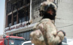 A member of the Iraqi security forces stands guard near the mall that was gutted by the deadly fire