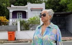 Gloria Cuevas poses in front of her former house in Rincon, Puerto Rico, which has been converted into an Airbnb