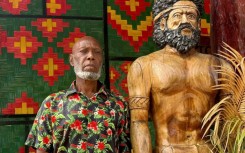 Head chief of the volcanic island of Ambrym, George Bumseng, stands next to a wooden statue in the Vanuatu capital of Port Vila on July 24, 2025