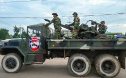 Cambodian soldiers stand on a military truck with an anti-aircraft gun in Oddar Meanchey province