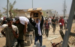 A Palestinian woman carries a food parcel as people return to the Nuseirat refugee camp from a US-backed Gaza Humanitarian Foundation distribution point near the Netsarim corridor in the central Gaza Strip