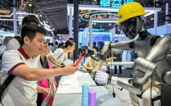 People watch a robot performing tasks at an exhibition during the World AI Conference in Shanghai