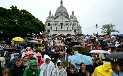 Spectators gather under umbrellas as they await the arrival of the Tour de France riders at the Sacre-Coeur basilica in Montmartre