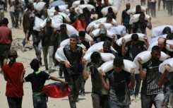 Palestinians carrying sacks of flour after trucks carrying humanitarian aid entered northern Gaza