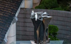 Two yellow-crested cockatoos resting atop a statue in Hong Kong Park