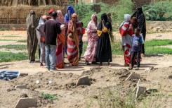 Bereaved relatives gather by the makeshift graves, waiting for the chance to give their loved ones a proper burial