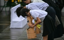 Schoolchildren make a ceremonial water offering during a memorial event marking the 80th anniversary of the US atomic bombing of Nagasaki