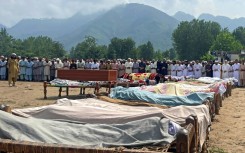 Mourners gather for mass funerals, where bodies wrapped in shawls were laid out on the village ground