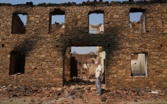 A man stands in front of a ruined burnt house after a wildfire in the village of Castrocalbon, northwestern Spain