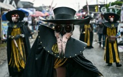 Costumed dancers perform as they follow a truck mounted with a tower of subwoofers and spotlights during a "sound horeg"